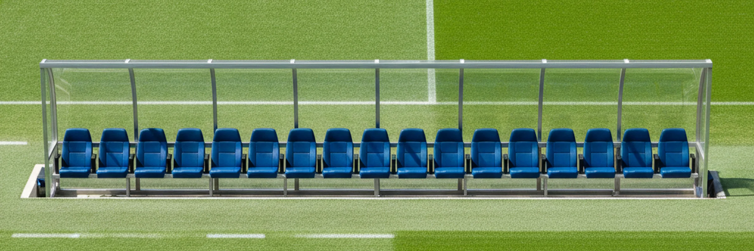Empty stadium dugout bench beside a vivid green pitch